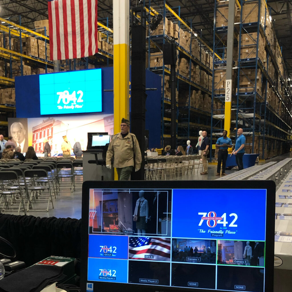 Large screens fill up a warehouse space with chairs filling the room.