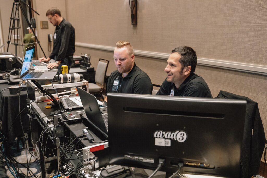 Two audio technicians sit behind computer monitors 