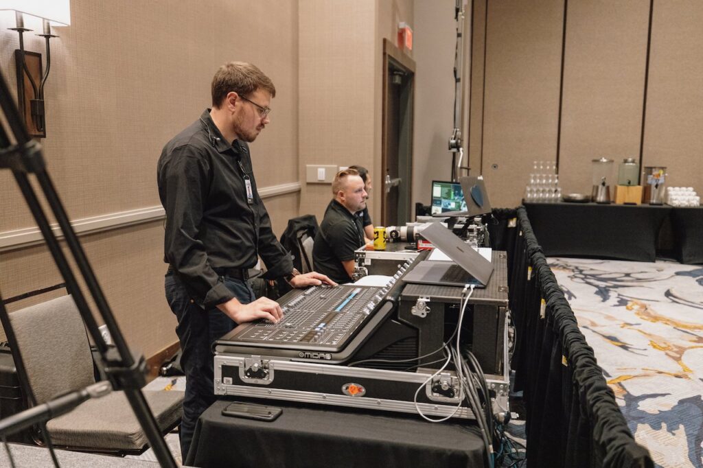 An audio technician sits behind a console while the event takes place
