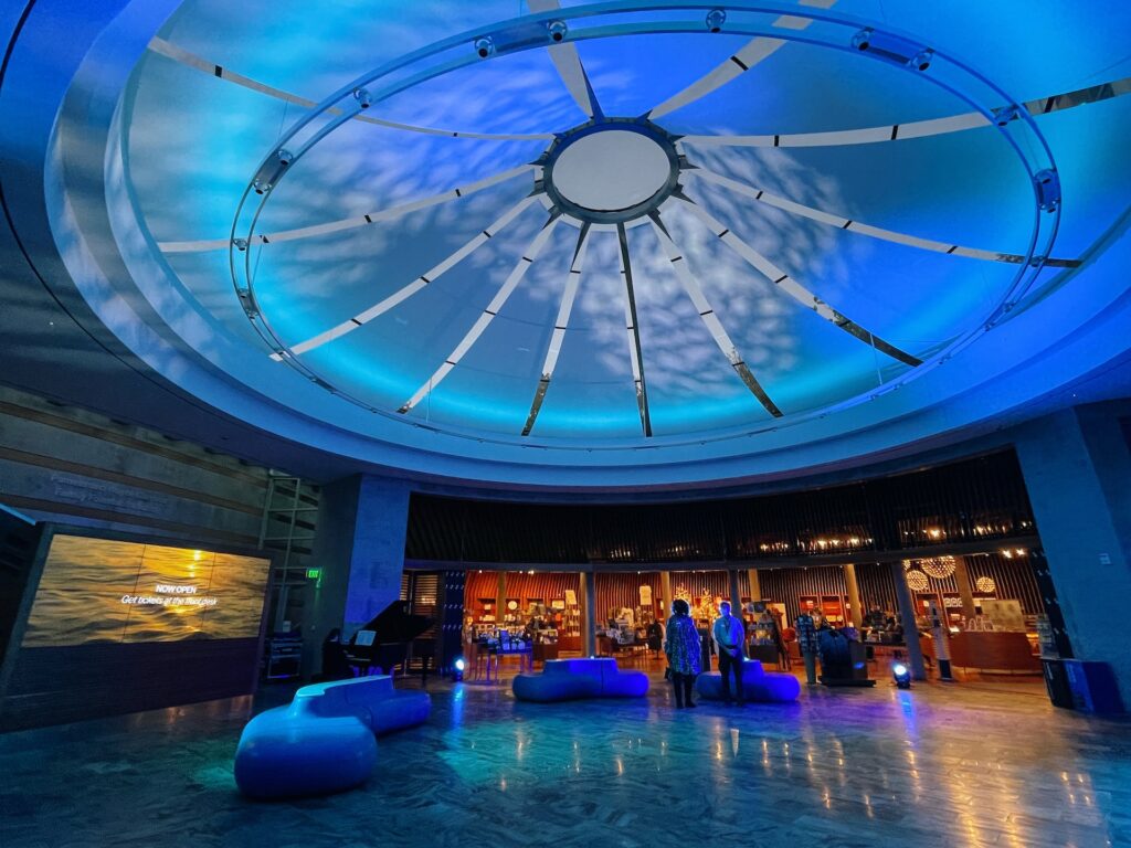Blue circular art sits on top of a ceiling of a large room.
