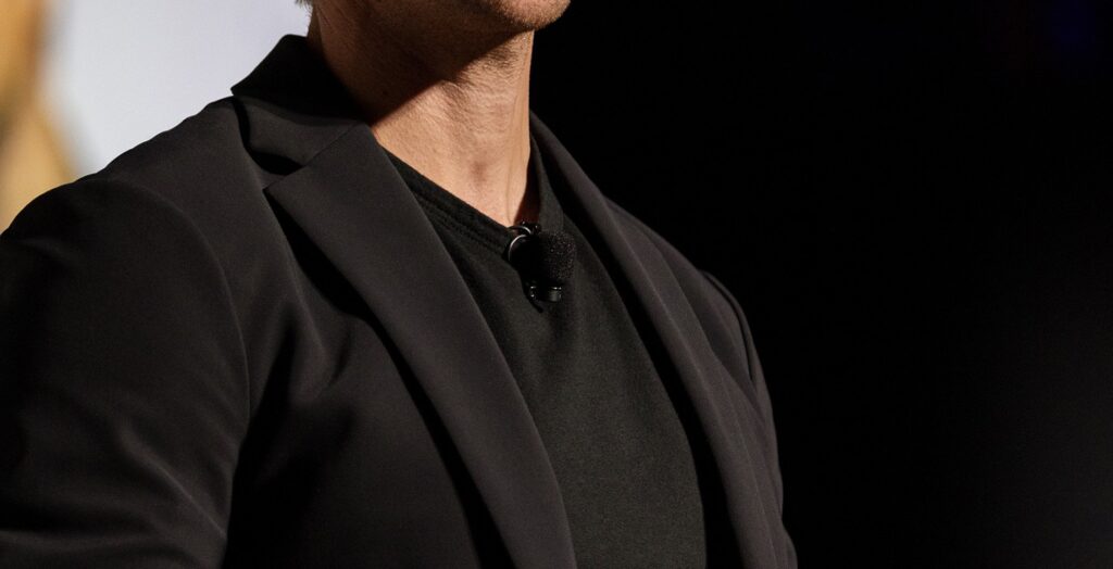 Lavalier microphone attached to a presenters black shirt. 