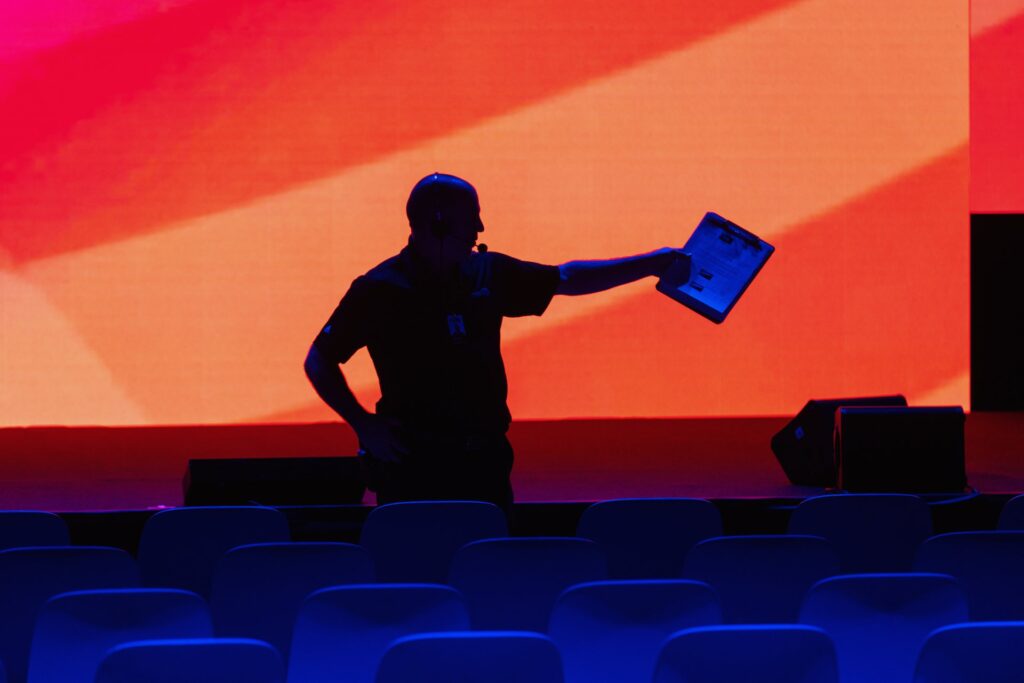 Production manager stands pointing backlit from an American flag LED wall behind him.