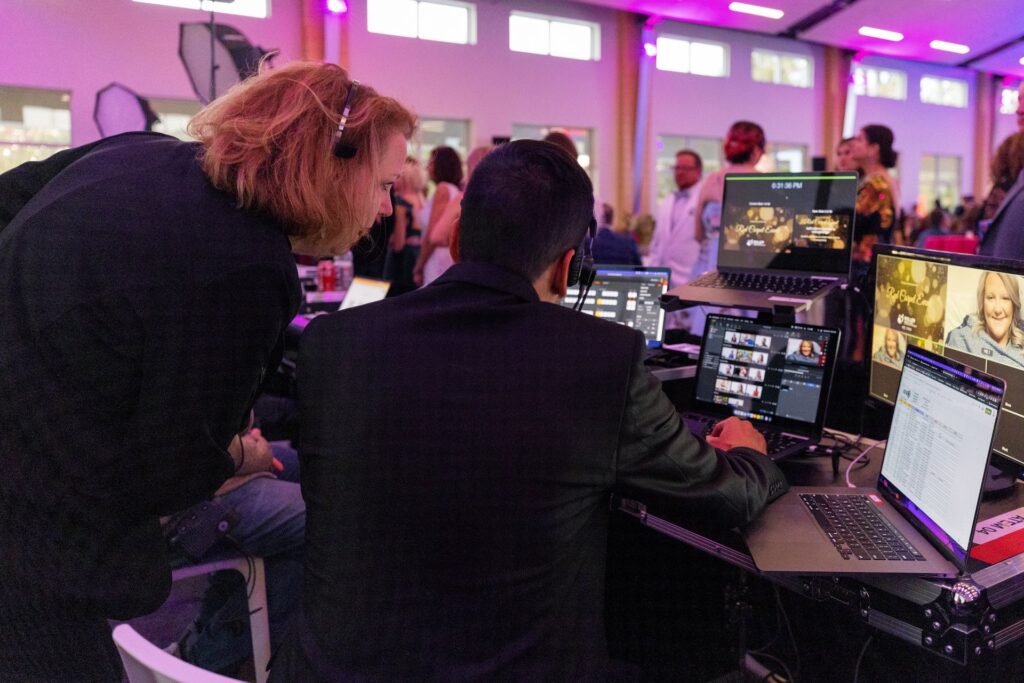 A graphics tech and production manager talk about details during a show in a purple lit room.