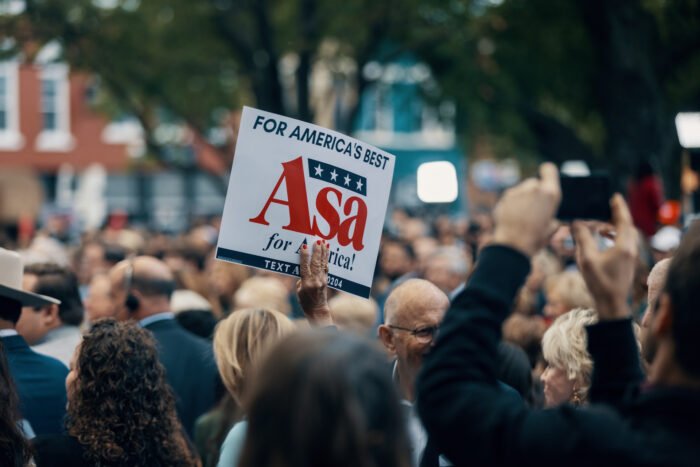 In a crowd of people, a hand sticks out and holds up a sign reading; " For America's best. Asa for America!" 
